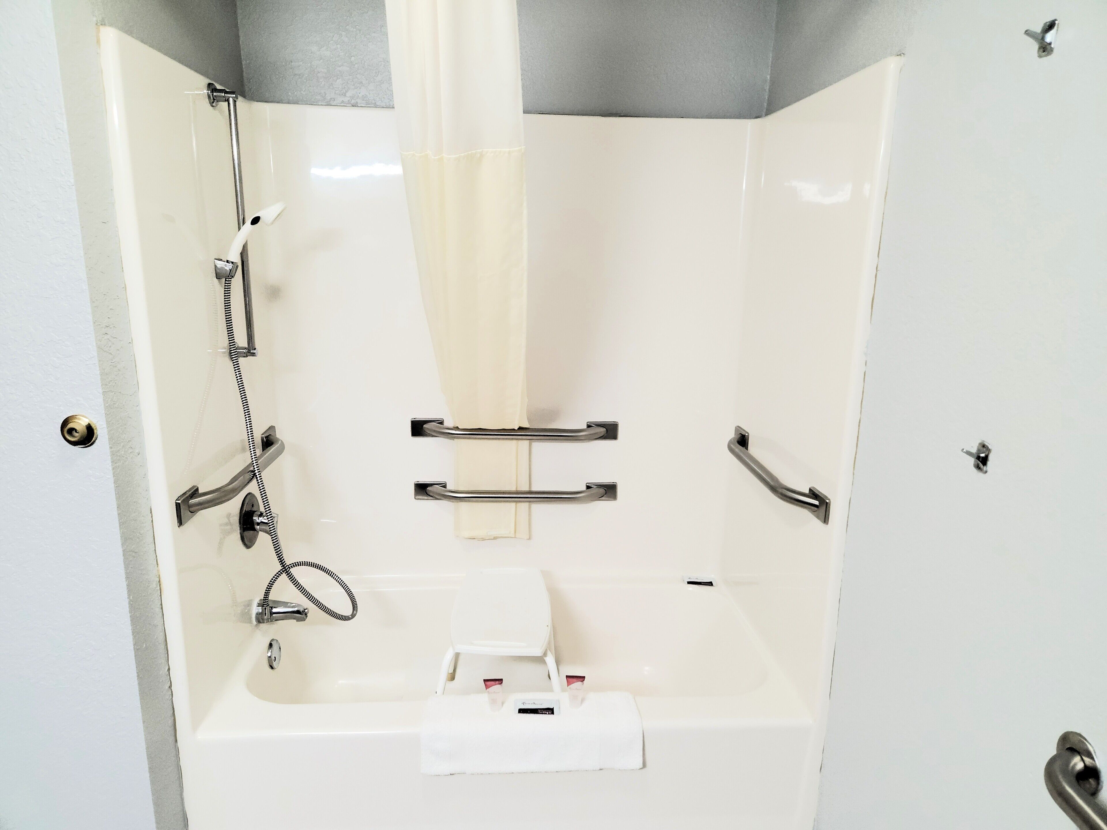 A shower with a handheld showerhead, a towel rack, and a soap dish.