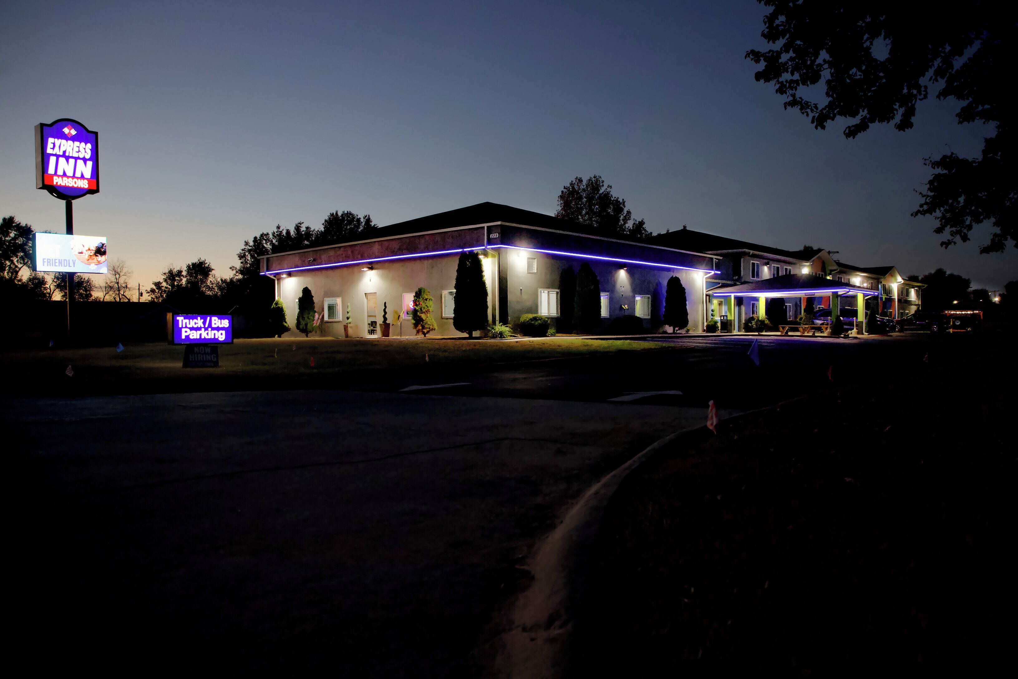 A hotel with a sign for 'Express Inn Parsons' and a 'Truck / Bus Parking' sign.