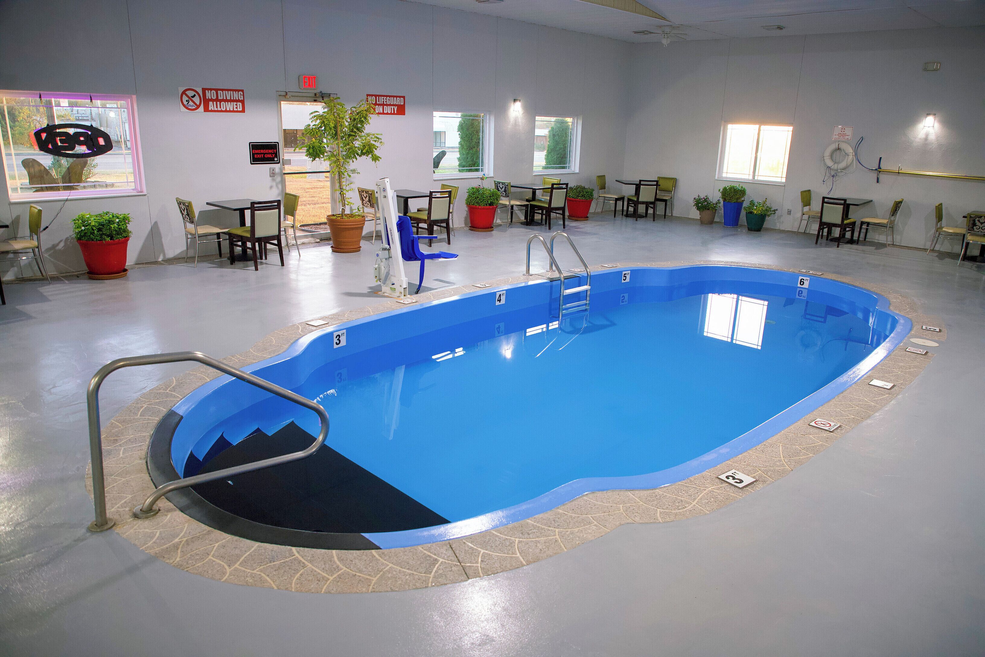 Ein Innenpool mit blauer Gestaltung, umgeben von Tischen, Stühlen und Zimmerpflanzen.