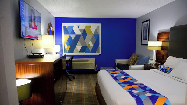 Une chambre d’hôtel avec un lit, un bureau et une télévision.
