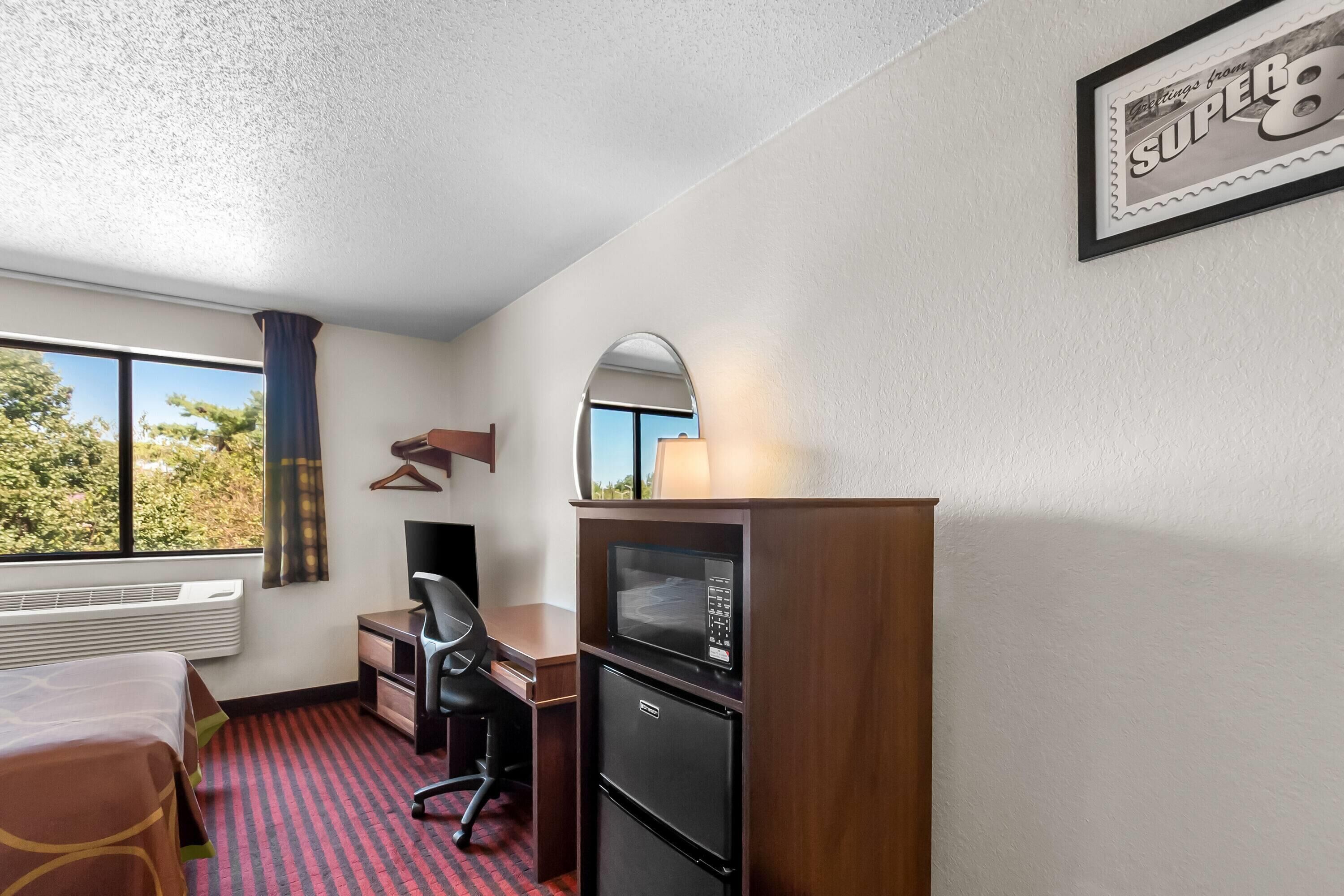 Una habitación de hotel con escritorio, silla, cama y minibar.