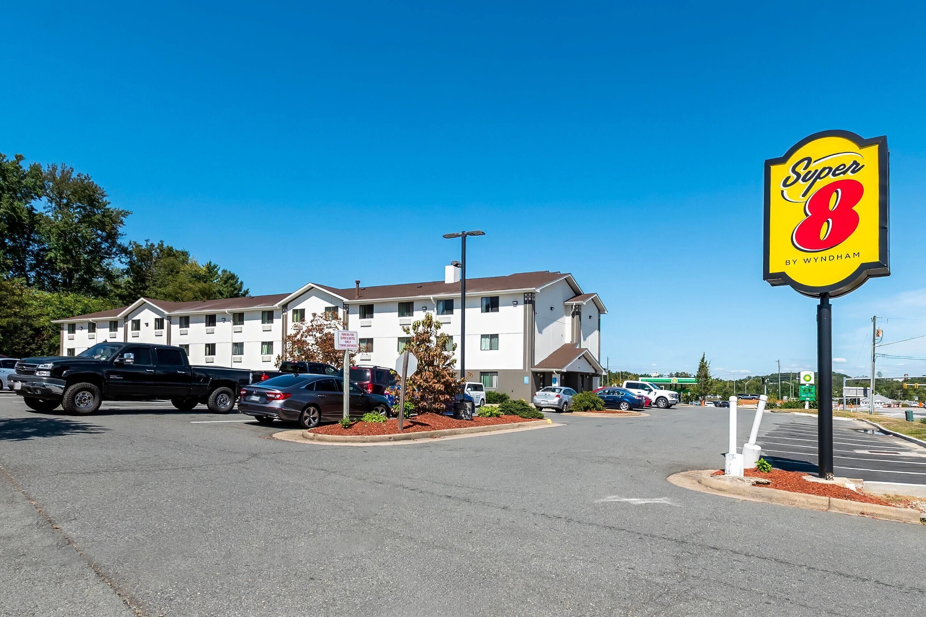 A Super 8 motel with a parking lot, a black pickup truck, and a clear blue sky.