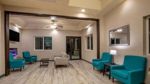 A spacious living area with teal armchairs, a white sofa, a small table, and a ceiling fan. - Super 8 by Wyndham Gillette (Gillette)