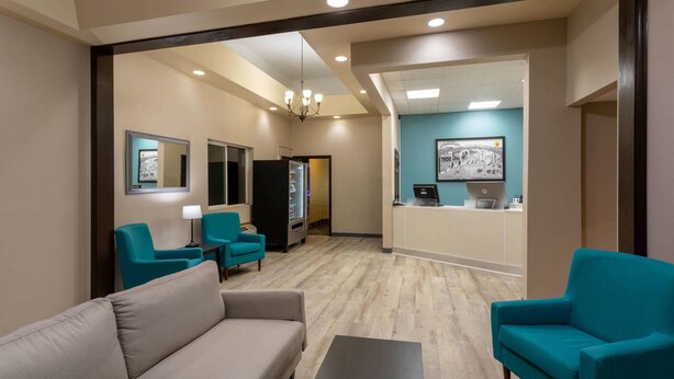 A hotel lobby with a sofa, two armchairs, a coffee table, a reception desk, and a refrigerator. - Super 8 by Wyndham Gillette (Gillette)