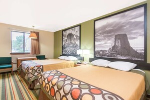 Habitación de hotel con dos camas, una ventana con cortinas, una lámpara y cuadros grandes enmarcados en la pared.