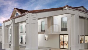 A modern two-story building with a flat roof, large windows, and a balcony.