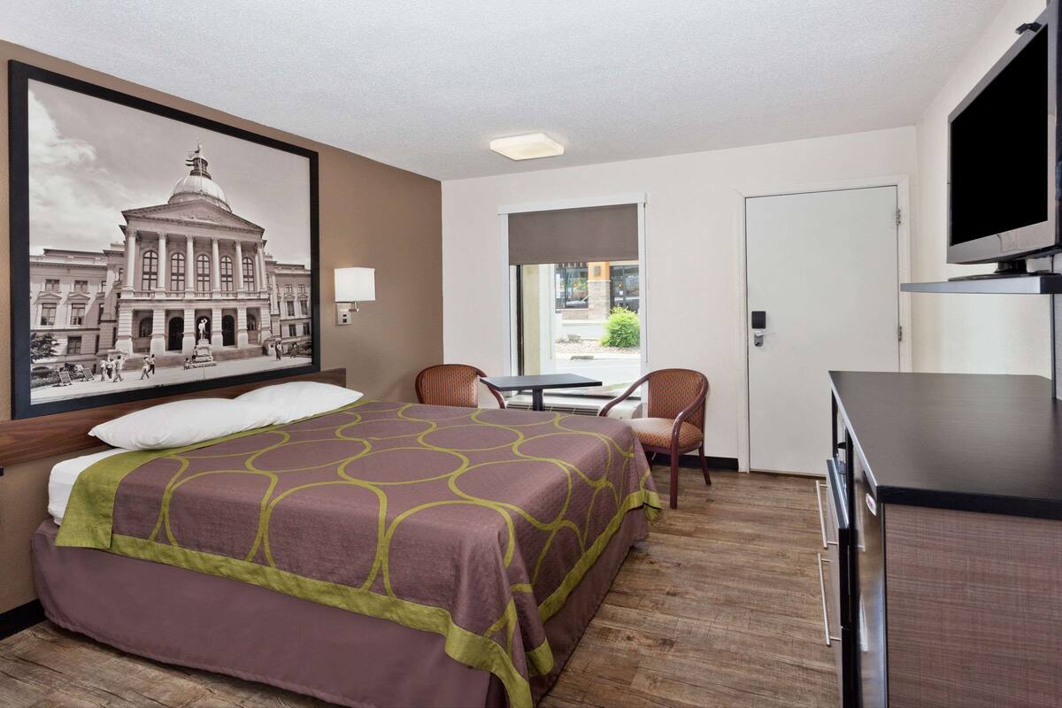 Une chambre d’hôtel avec un grand lit, un bureau, une télévision et une fenêtre donnant sur l’extérieur.