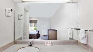 A bathroom with a large mirror, a sink, and a towel rack.