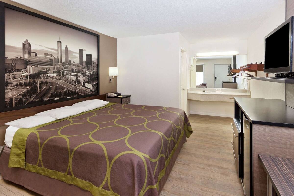 Une chambre d’hôtel comprenant un lit, un bureau, une télévision, une salle de bain et offrant une vue sur la ville.