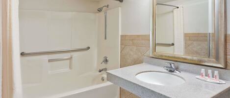 A bathroom with a bathtub, a sink, and a mirror.