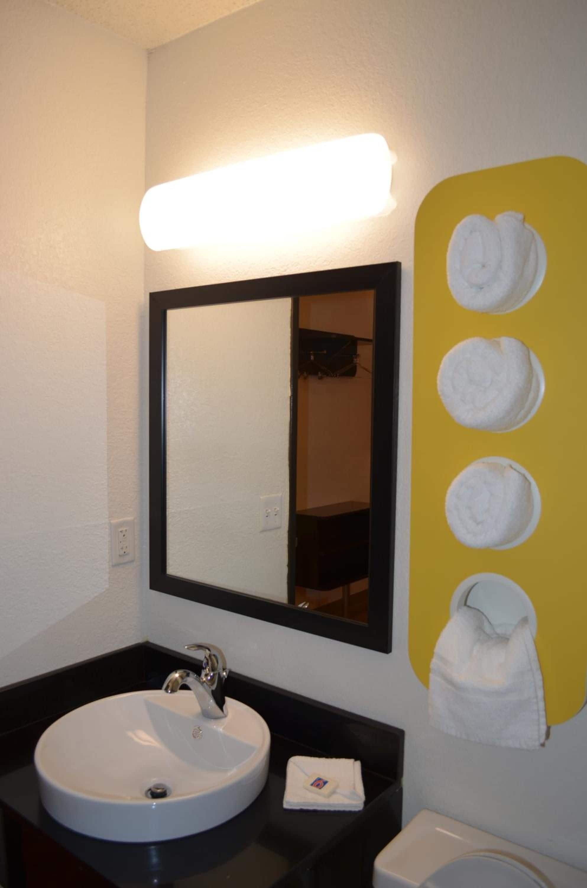 A bathroom with a sink, mirror, and towel rack.