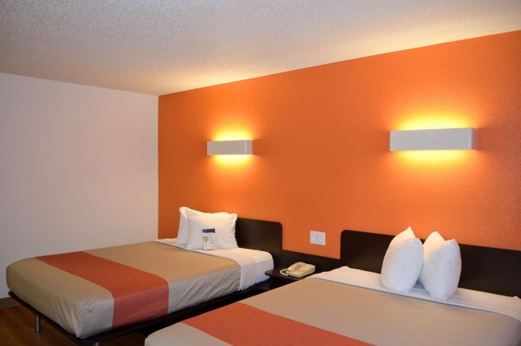Une chambre d’hôtel avec deux lits, chacun étant équipé d’un oreiller et d’une table de chevet.