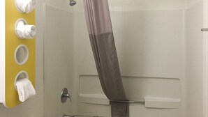 A bathroom with a shower, a towel rack with multiple towels, and a curtain. - Motel 6 Kingsland, GA - Kings Bay Naval Base (Kingsland)