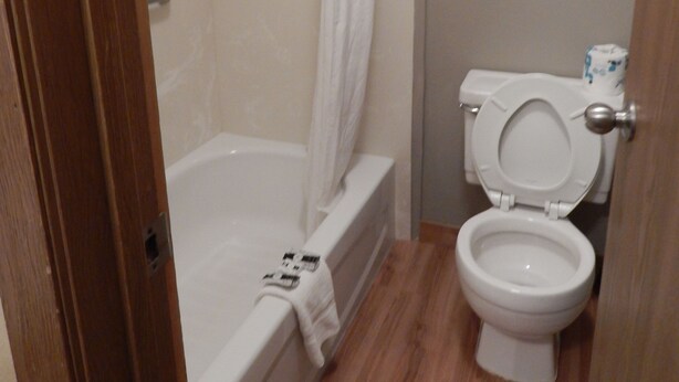 A bathroom with a bathtub, toilet, and shower curtain. - Alpine Inn of Pagosa Springs (Pagosa Springs)