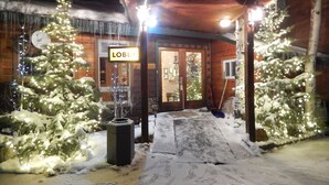A wooden lodge with a 'Lobby' sign, snow-covered trees, and a snow-covered entrance. - Alpine Inn of Pagosa Springs (Pagosa Springs)