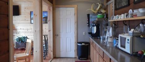 A wooden interior with a kitchen area, including a microwave, sink, and various kitchen utensils.