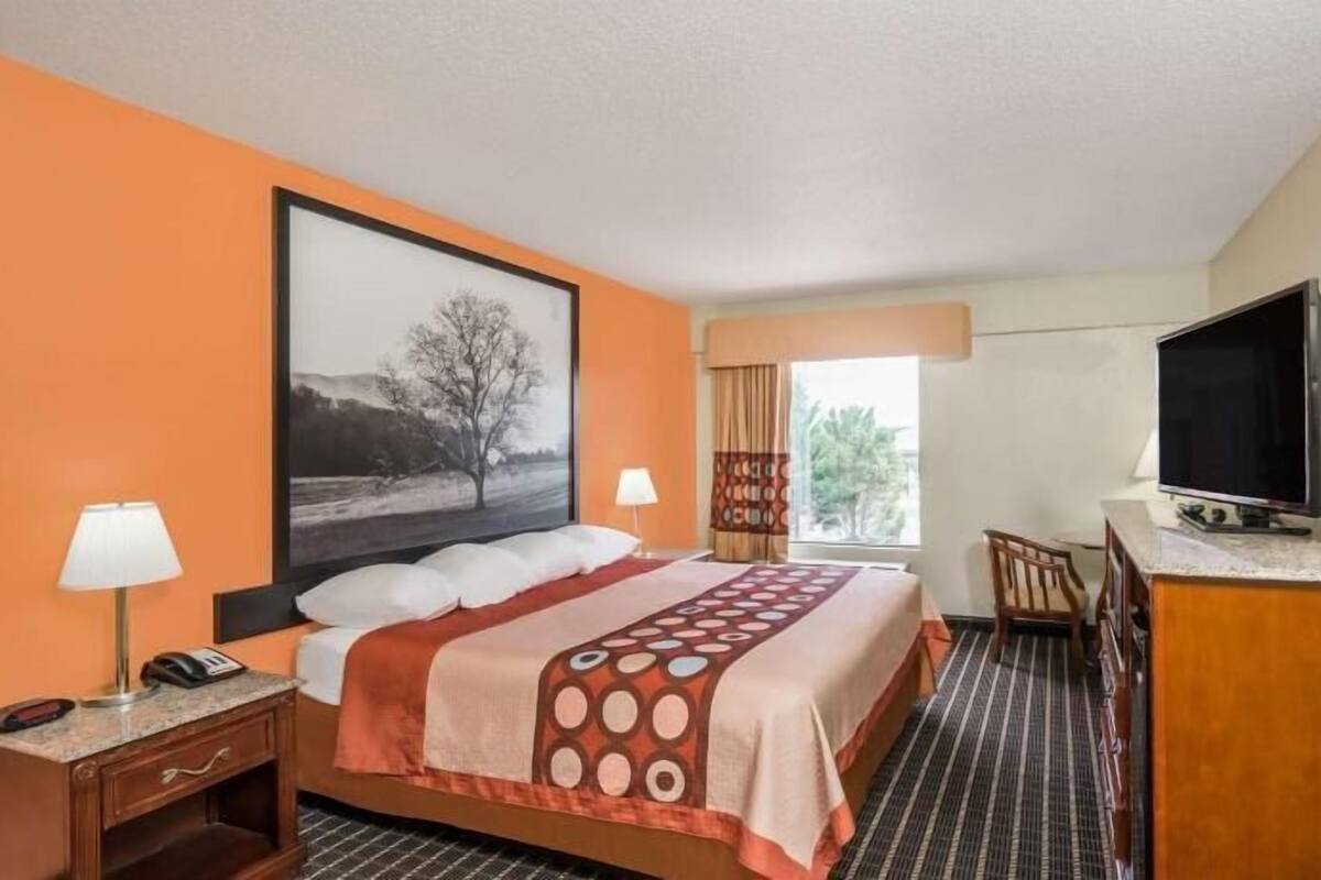 Hotelkamer met een bed, een bureau, een televisie en een raam met gordijnen.