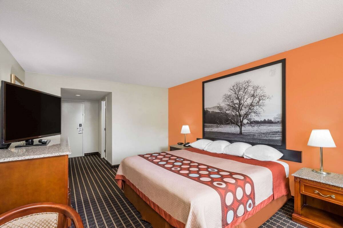 Een hotelkamer met een bed, een televisie, een bureau en een groot raam.