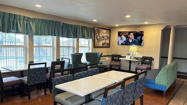 A restaurant with a long table, several chairs, and a television on the wall. - Super 8 by Wyndham San Antonio/Fiesta (San Antonio)