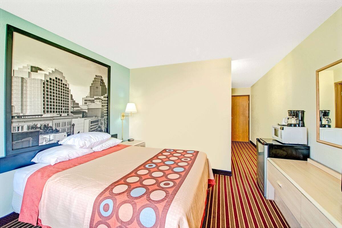 Ein Hotelzimmer mit Bett, Schreibtisch mit Mikrowelle, Spiegel und Blick auf die Stadt.
