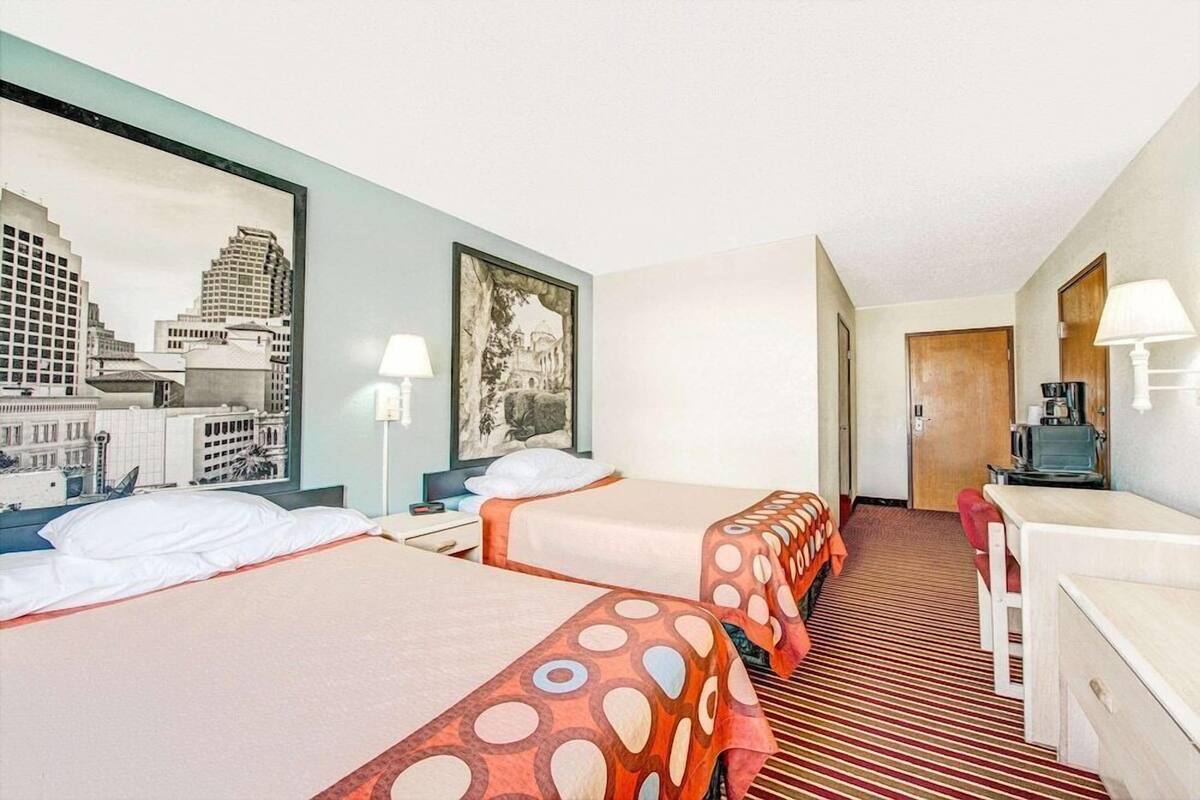 Ein Hotelzimmer mit zwei Betten, einem Schreibtisch, einem Stuhl und Blick auf die Stadt.