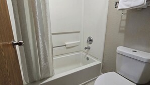 A bathroom with a bathtub, toilet, and a wooden door. - Super 8 by Wyndham San Antonio/Fiesta (San Antonio)