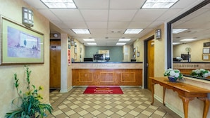 A reception area with a registration desk, a red carpet, and a wooden table with a flower vase.