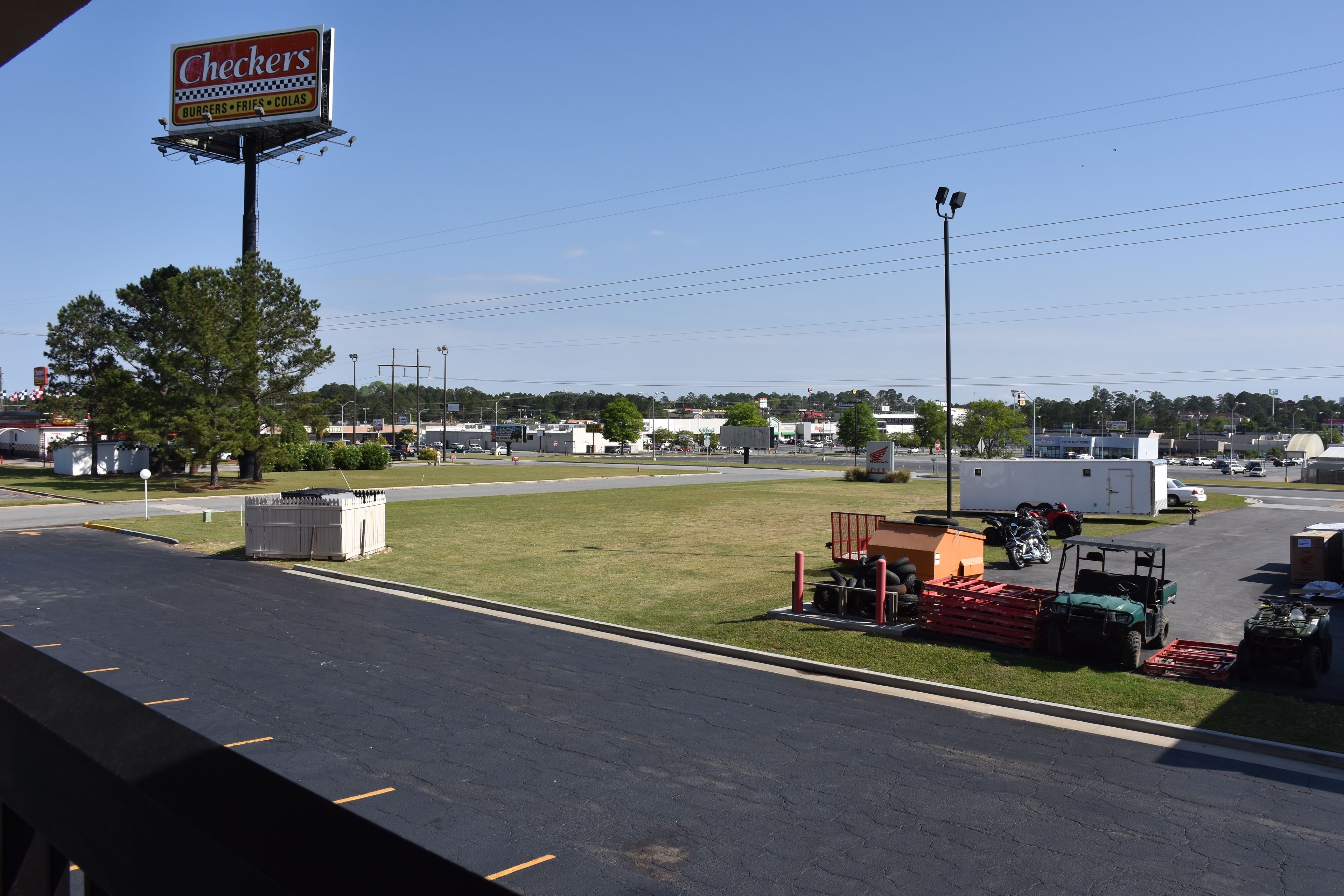 A parking lot with a Checkers restaurant sign, a grassy area, and a few vehicles.