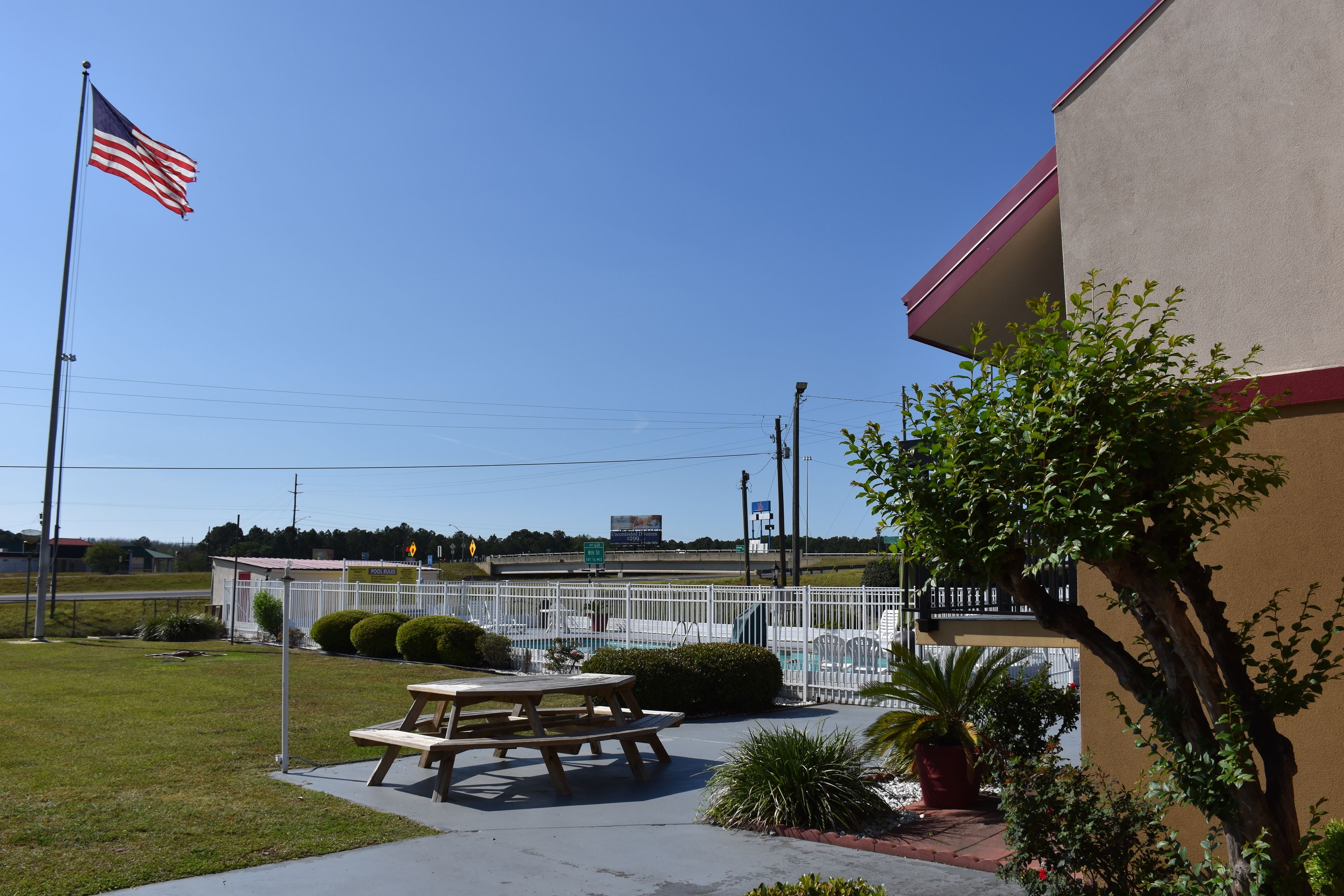 A picnic table and benches in a grassy area with a building in the background.
