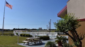 A picnic table and benches in a grassy area with a building in the background.