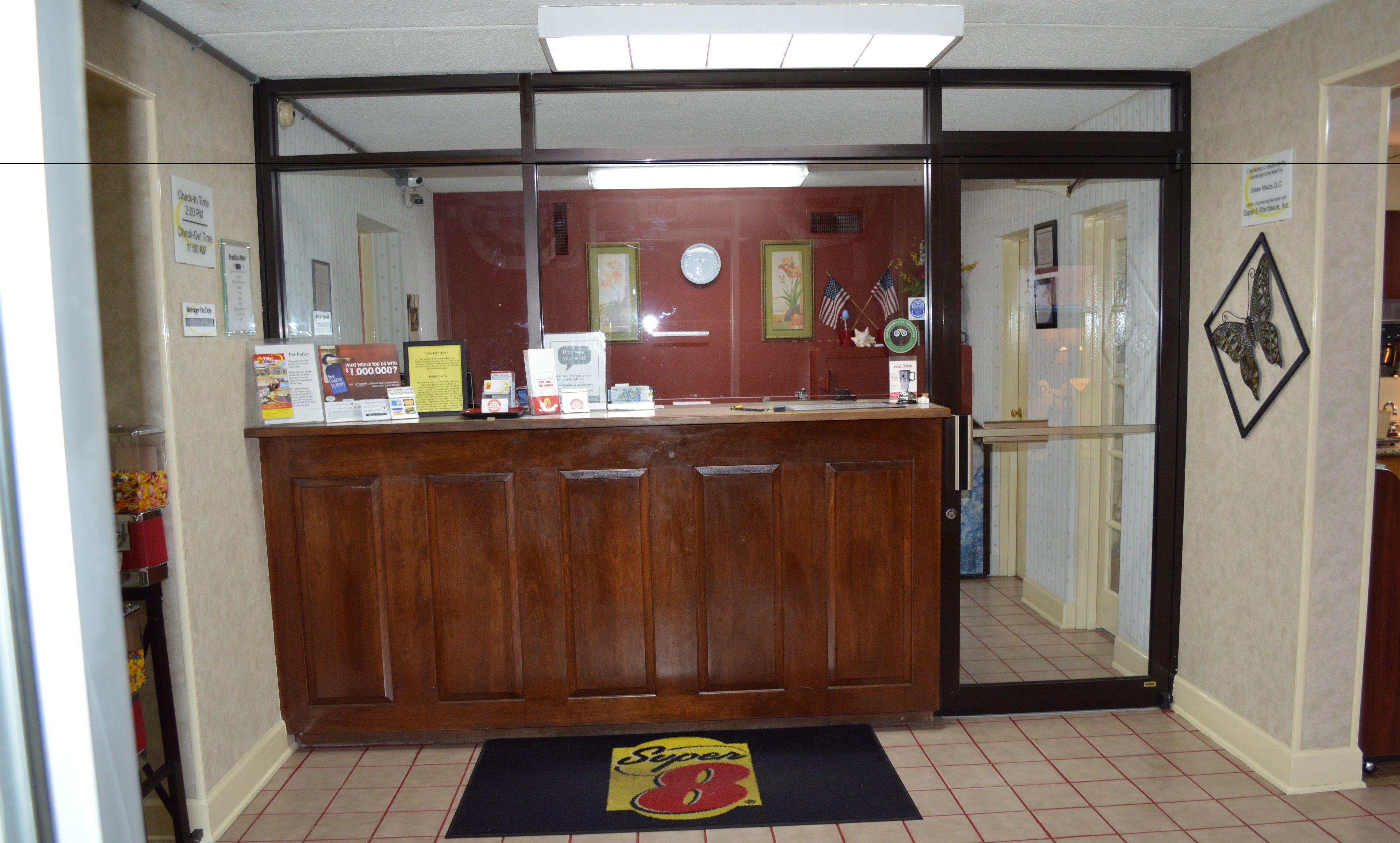 A reception desk with a check-in counter, a clock, and various informational signs.