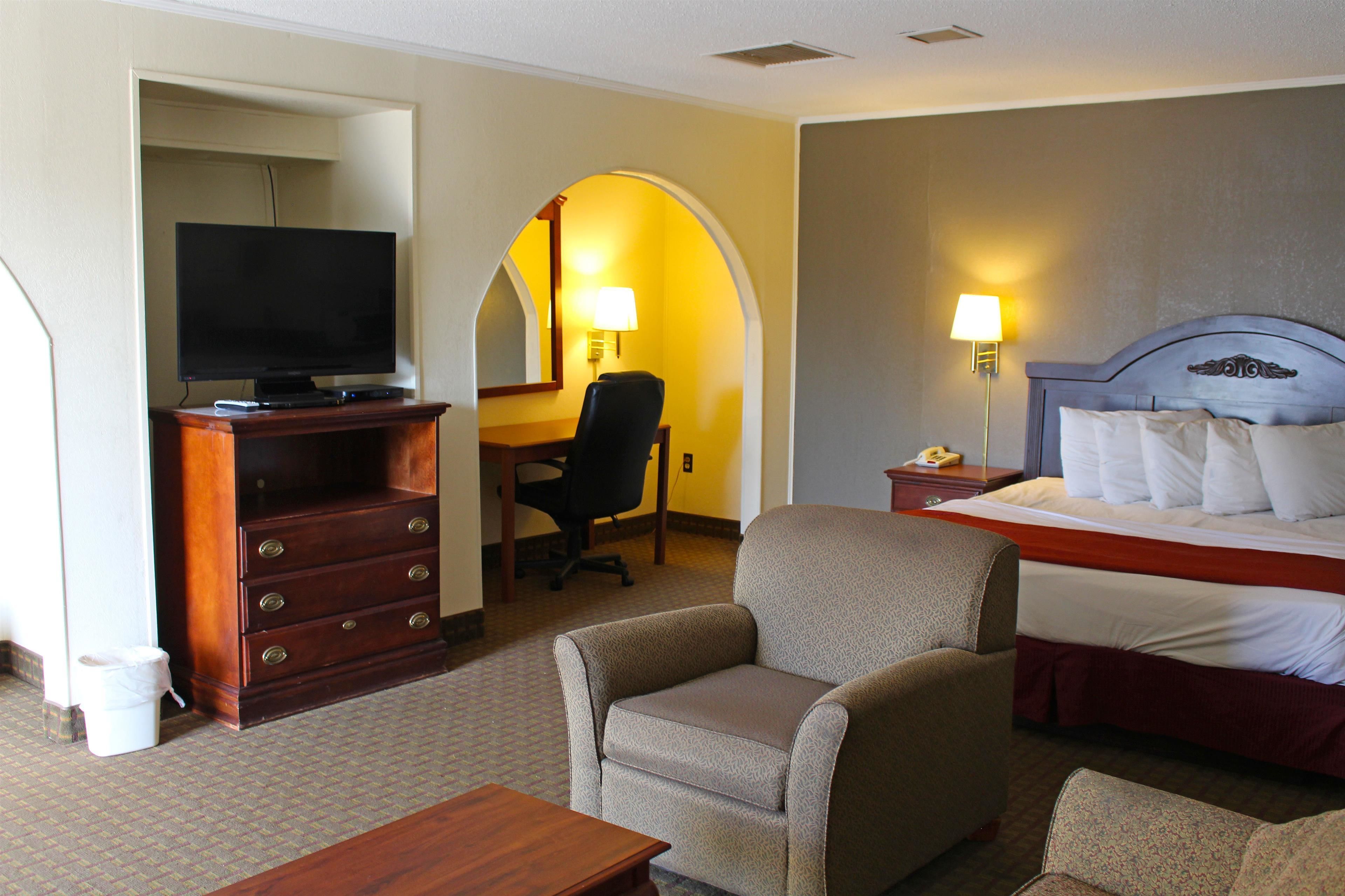 Een hotelkamer met een bed, een televisie, een bureau met een stoel en twee lampen.