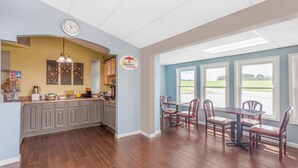 A spacious kitchen with a dining area, wooden flooring, and a view of the outdoors.