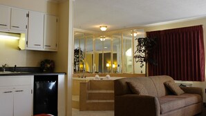 A compact living space with a kitchenette, a sofa, and a staircase leading to a bathroom.