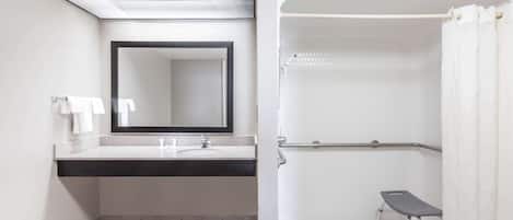 Un baño con lavamanos, espejo y ducha.