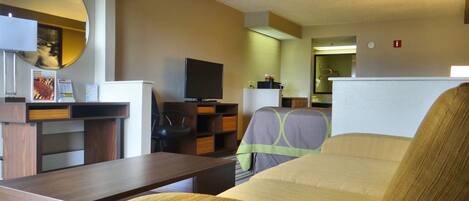 A hotel room with a bed, a desk, a television, and a mirror.