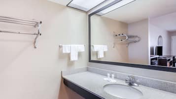 Un baño con lavamanos, espejo, toallero y una toalla colgada en la pared.