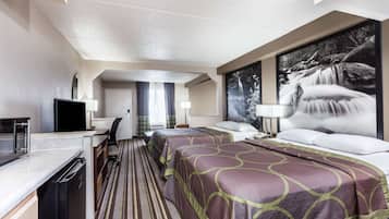 Une chambre d’hôtel avec une kitchenette, deux lits, une grande fenêtre et un tableau représentant une cascade.
