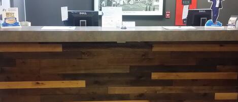 A reception desk with a wooden panel design, a framed welcome sign, and a Dell computer station.