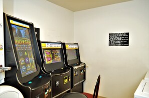 A row of gaming machines in a room with a white wall and a sign with instructions. - Super 8 by Wyndham Clearfield (Clearfield)