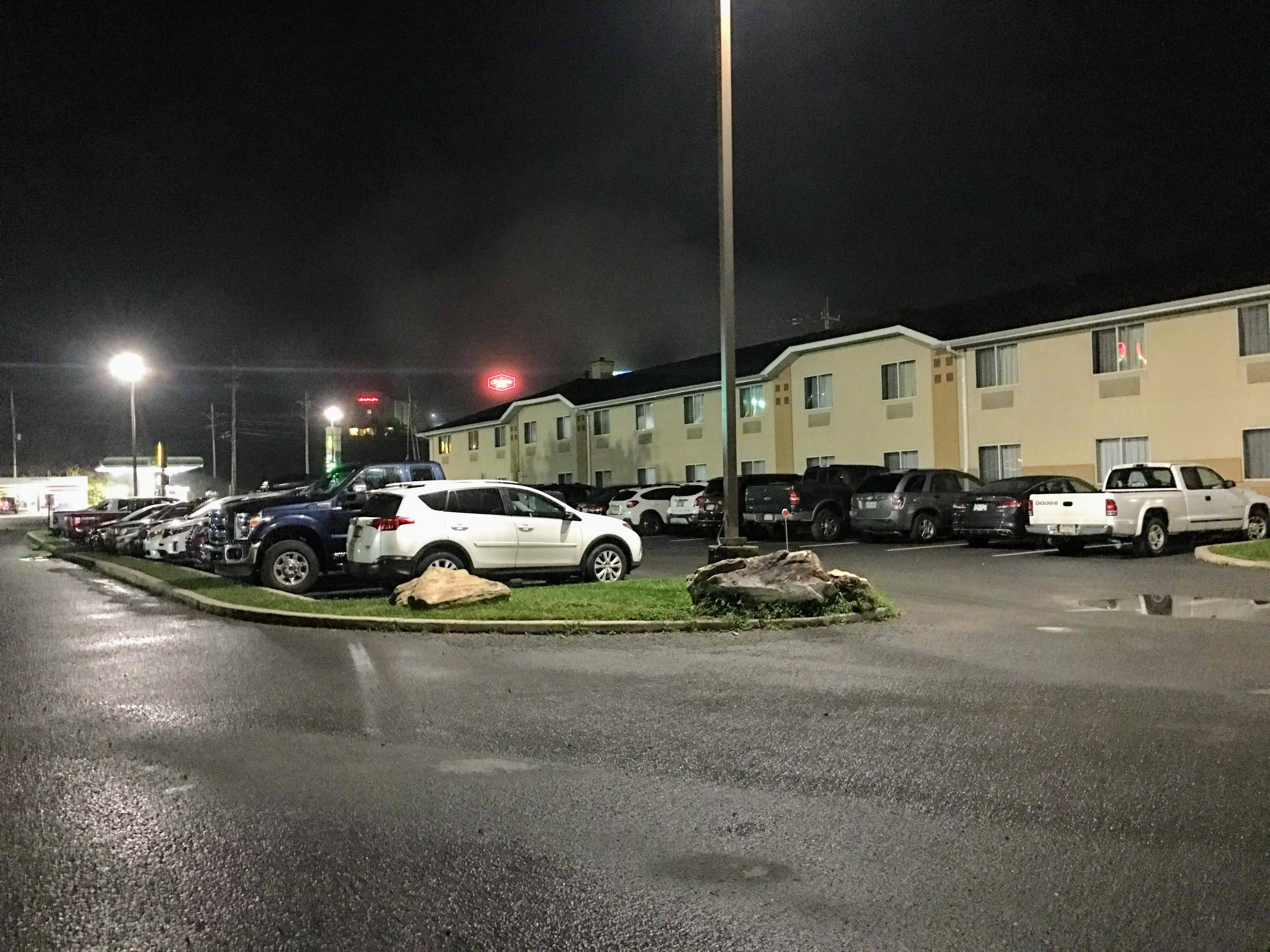 Un estacionamiento con varios coches y un edificio al fondo.