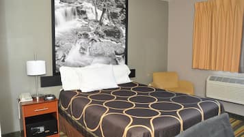 Une chambre d’hôtel avec un lit, une table de chevet avec une lampe, un téléphone et une grande photographie en noir et blanc représentant une cascade.