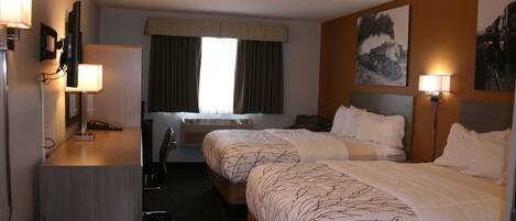 A hotel room with two beds, a desk, a chair, a TV, and a window with curtains.
