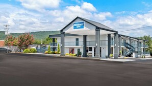 A motel with a prominent sign, a covered parking area, and a staircase leading to the entrance. - Rodeway Inn Dalton South (Dalton)