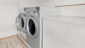 A modern laundry room with two front-loading washing machines and a dryer. - Rodeway Inn Dalton South (Dalton)