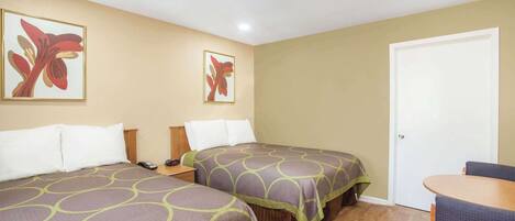 Habitación de hotel con dos camas, un escritorio, una silla y una puerta.
