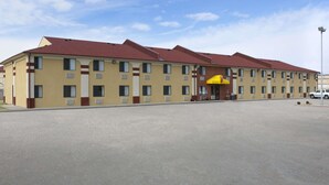 Um hotel com vários andares, fachada amarela e telhados vermelhos. Possui entrada central com toldo amarelo.