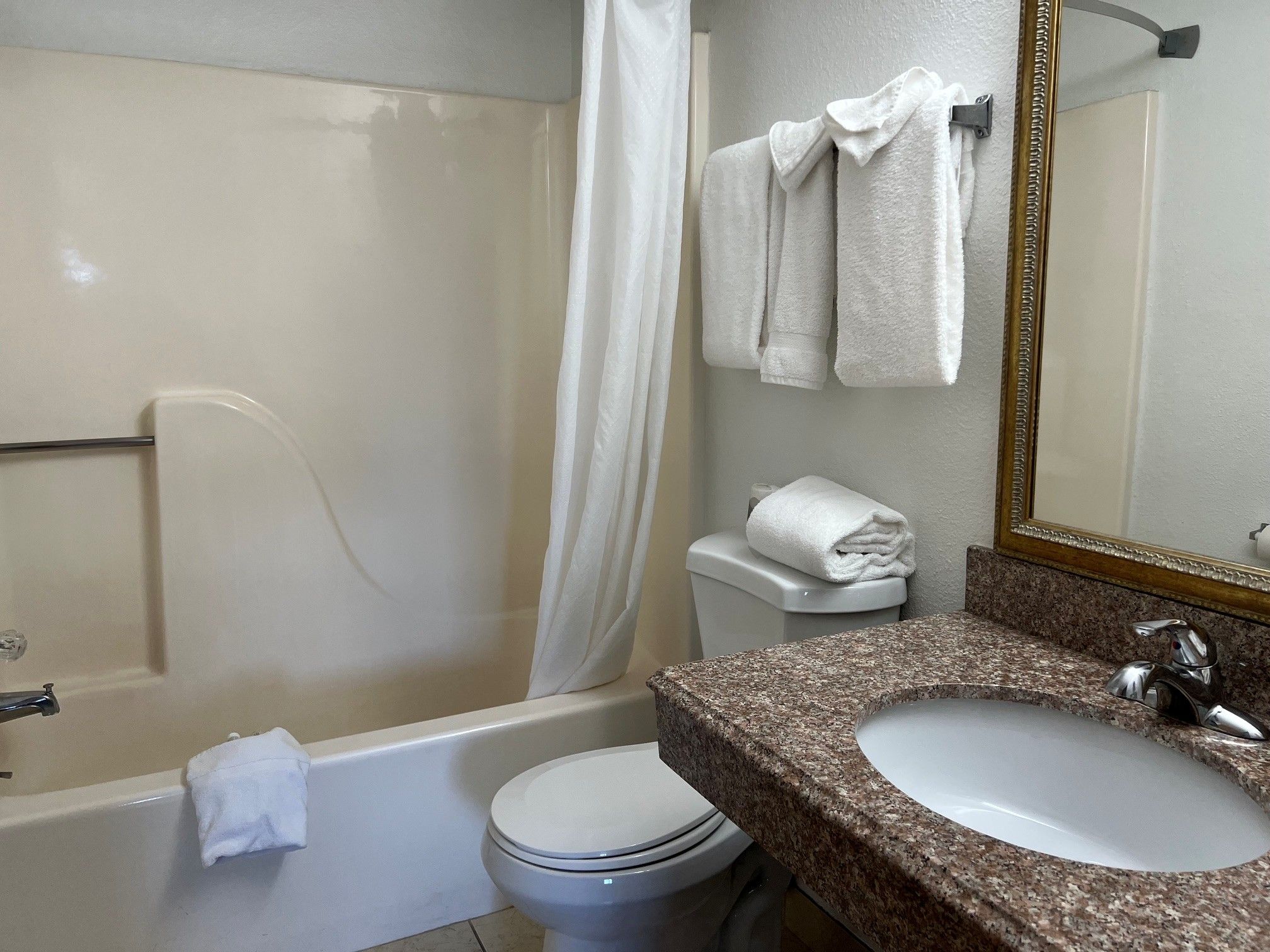 A bathroom with a bathtub, toilet, sink, and a mirror.