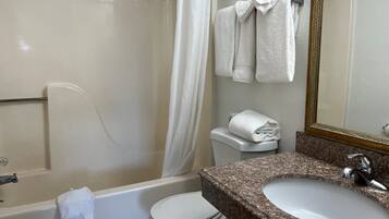 A bathroom with a bathtub, toilet, sink, and a mirror.