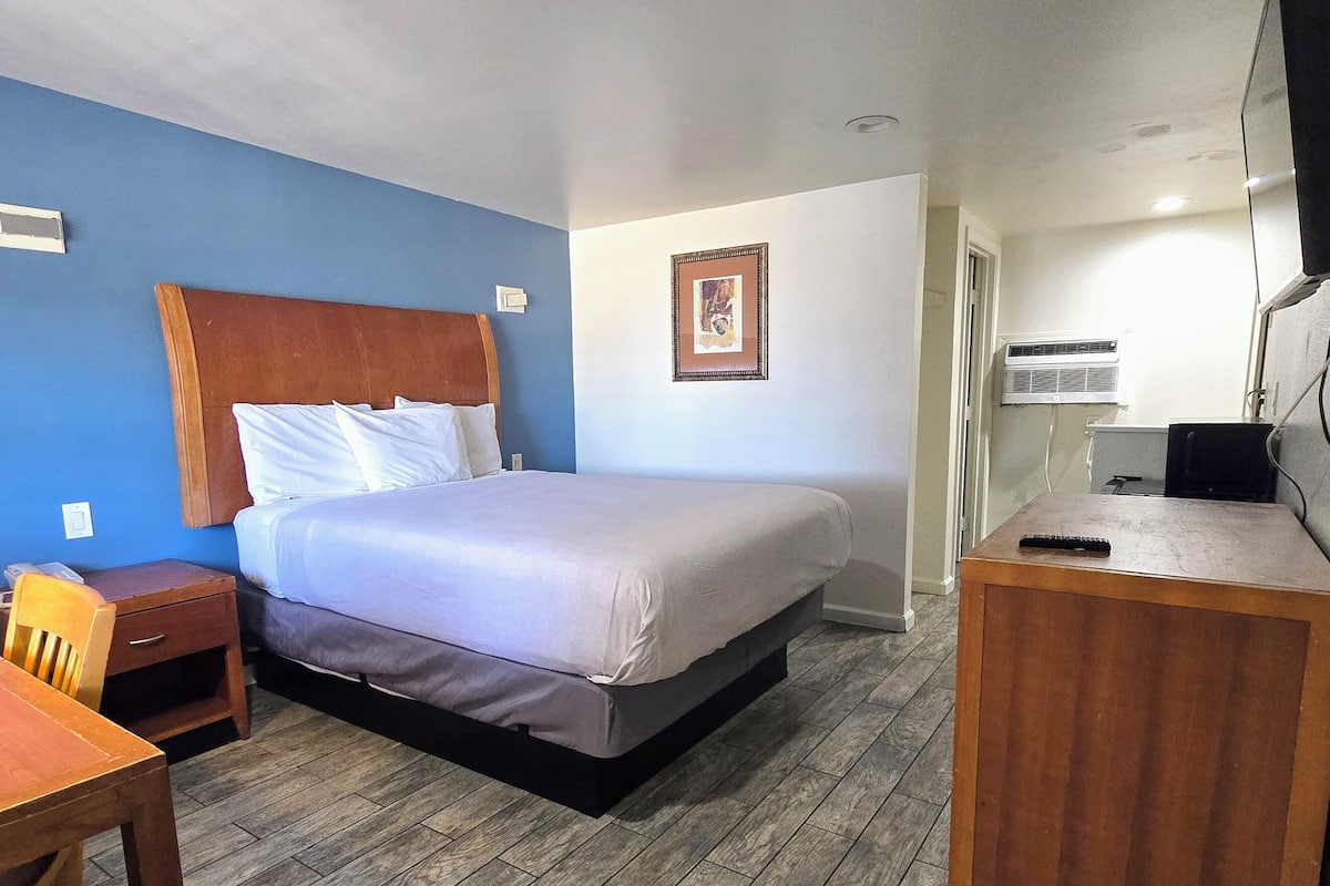 A hotel room with a bed, a desk, a chair, and a picture on the wall.
